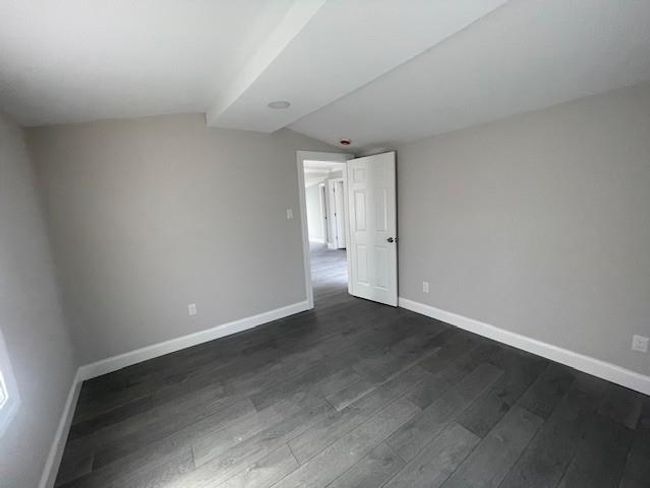 Unfurnished room featuring dark wood finished floors, vaulted ceiling, and baseboards | Image 7