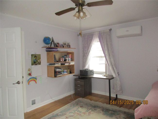 Bedroom featuring visible vents, baseboards, an AC wall unit, crown molding, and wood finished floors | Image 17