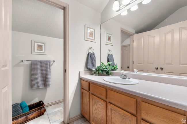 Bathroom featuring vaulted ceiling, vanity, and tile patterned floors | Image 17