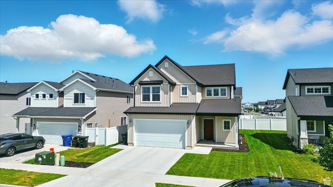 View of front of property with board and batten siding, concrete driveway, a garage, and a residential view | Image 22