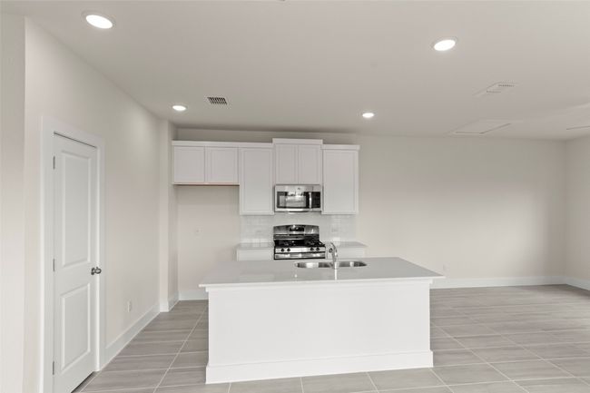 Kitchen with decorative backsplash, baseboards, white cabinetry, a sink, and stainless steel appliances | Image 13