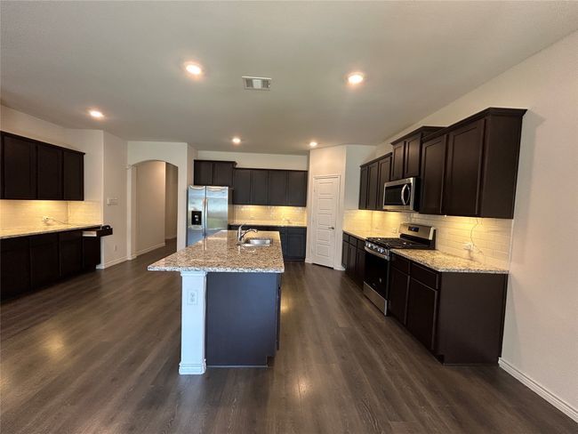 Kitchen featuring stainless steel appliances, a sink, arched walkways, tasteful backsplash, and light stone counters | Image 29