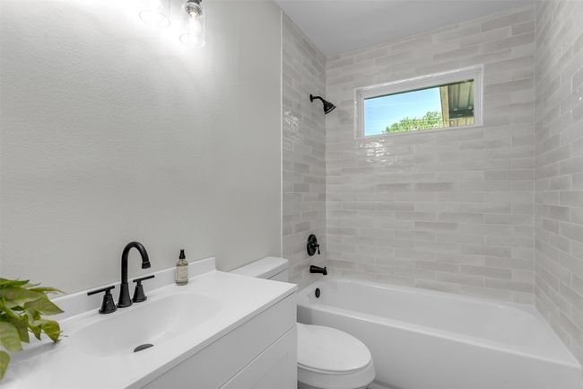 Full bathroom featuring toilet, washtub / shower combination, and vanity | Image 9