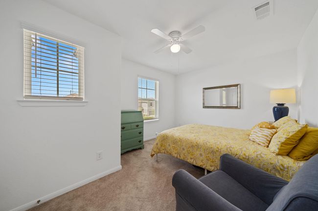 Spacious upstairs front room features plush carpeting and a ceiling fan, offering versatility as a bedroom or second living area. | Image 19