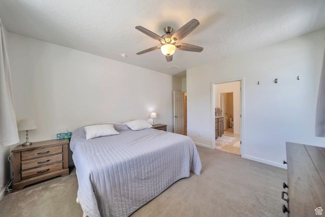 Bedroom with light carpet, a ceiling fan, ensuite bathroom, and baseboards | Image 12
