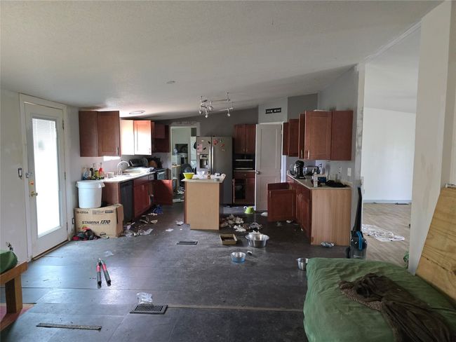 Kitchen with a center island, stainless steel refrigerator with ice dispenser, dishwasher, light countertops, and a sink | Image 4