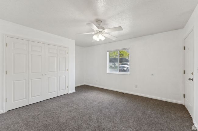 Unfurnished bedroom featuring carpet floors, a closet, a ceiling fan, and a textured ceiling | Image 15