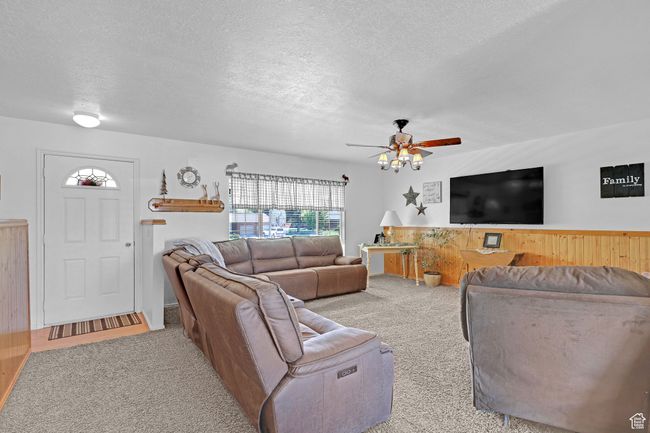Living area featuring carpet, a textured ceiling, and ceiling fan | Image 7
