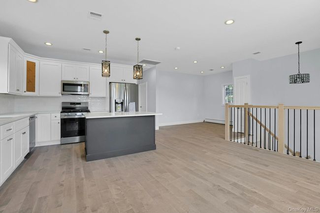 Kitchen featuring stainless steel appliances, light wood-type flooring, backsplash, recessed lighting, and a center island | Image 8