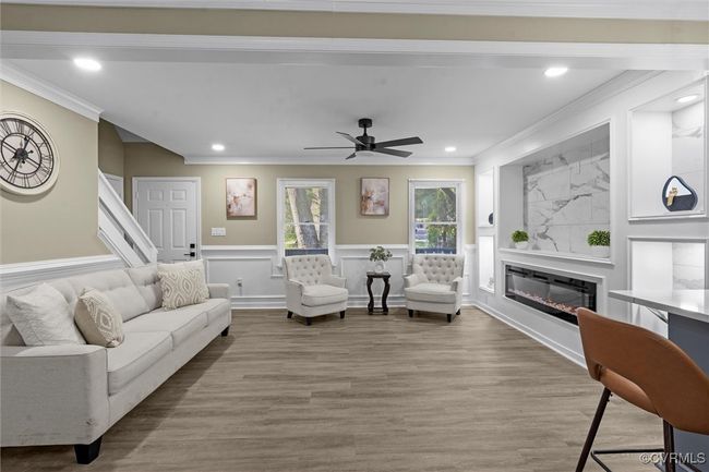 Living area with wood finished floors, recessed lighting, crown molding, wainscoting, and a glass covered fireplace | Image 12