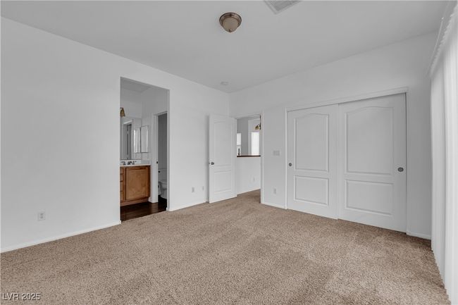Unfurnished bedroom featuring ensuite bathroom, a closet, baseboards, carpet flooring, and visible vents | Image 10