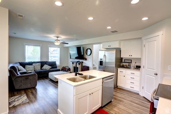 Kitchen featuring wood finished floors, a sink, open floor plan, visible vents, and appliances with stainless steel finishes | Image 7