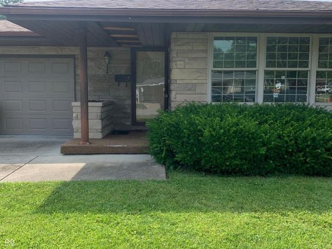 entrance to property with a yard, an attached garage, Bedford stone , and concrete driveway | Image 10