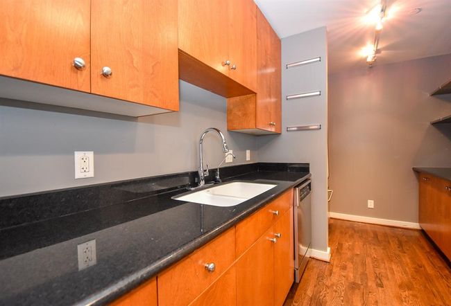 Another view of the kitchen showcasing the rich wood-colored cabinetry paired with sleek black countertops. | Image 20