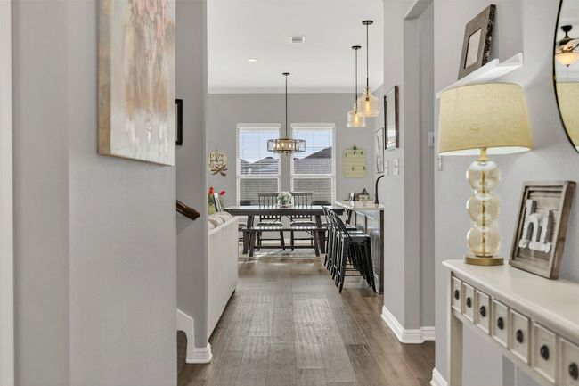 Hallway featuring visible vents, crown molding, baseboards, dark wood finished floors, and a notable chandelier | Image 6