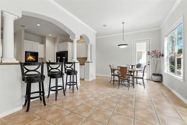 Dining room with light tile patterned floors, ornate columns, crown molding, a glass covered fireplace, and arched walkways | Image 18