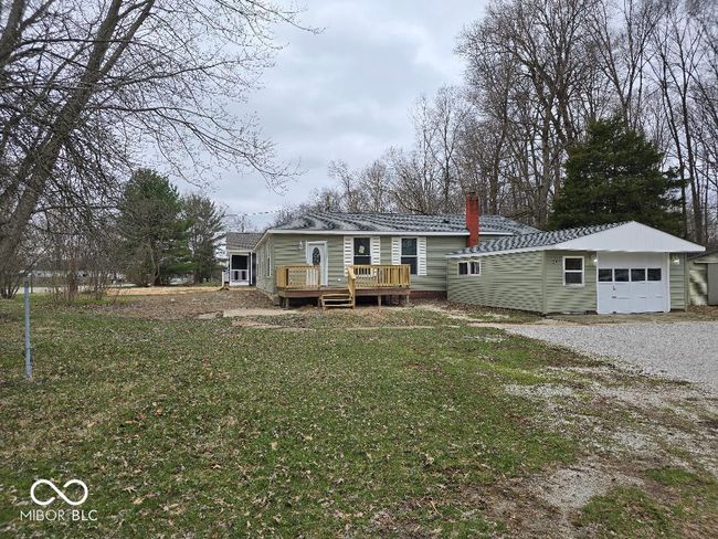 view of front of house with gravel driveway, a front lawn, a wooden deck, a chimney, and a garage | Image 10