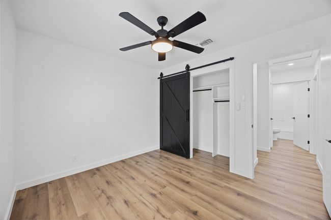 Unfurnished bedroom with light wood-style floors, a closet, a ceiling fan, and a barn door | Image 23