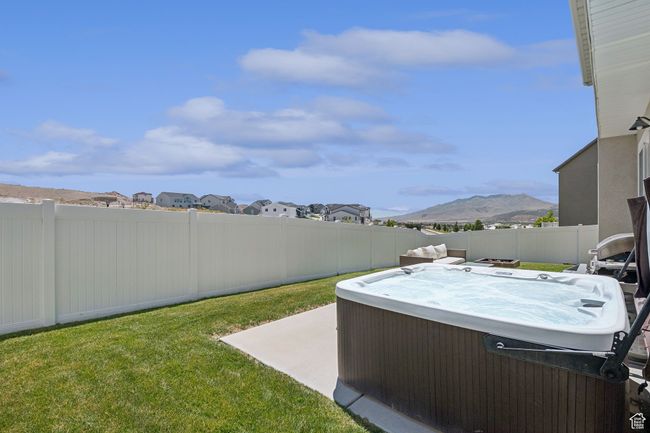 Fenced backyard with a hot tub, a mountain view, a patio, and a residential view | Image 29