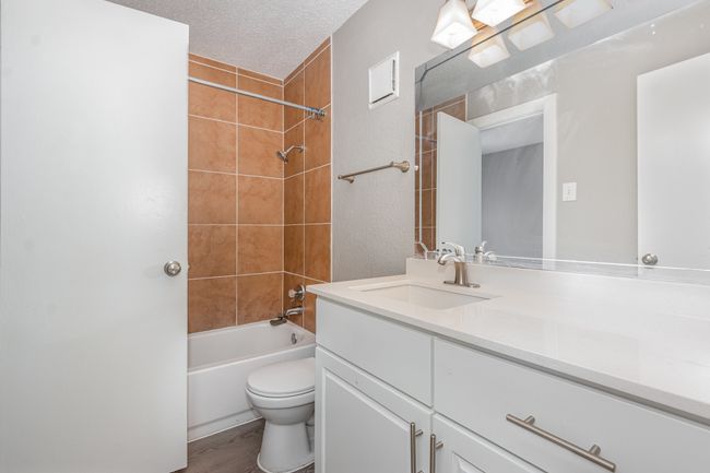 Bathroom with vanity, bathing tub / shower combination, toilet, wood finished floors, and a textured ceiling | Image 18