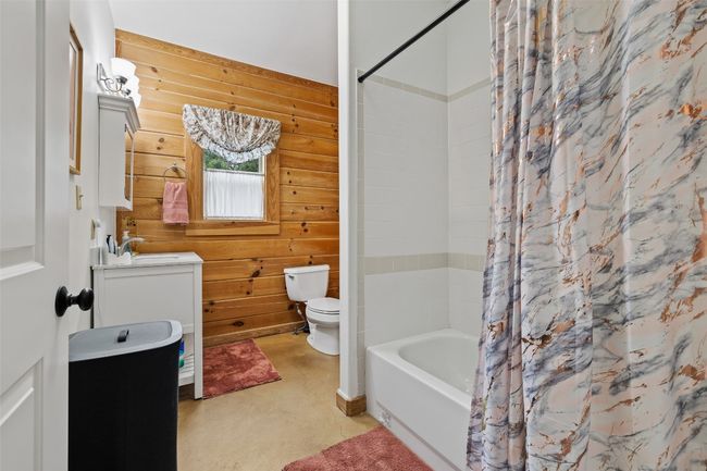 Full bath featuring vanity, wood walls and shower / tub combo | Image 30