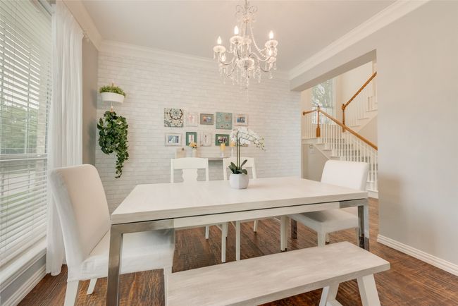 Dining area featuring a chandelier, stairs, crown molding, wood finished floors, and baseboards | Image 8