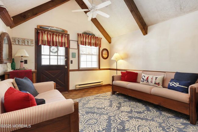 Sundrenched living room with vaulted beamed ceilings, skylight, Parquet wood floors and loft entry. | Image 13