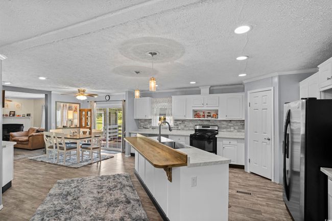 Kitchen featuring freestanding refrigerator, black gas range, a textured ceiling, wood finished floors, and ornamental molding | Image 40