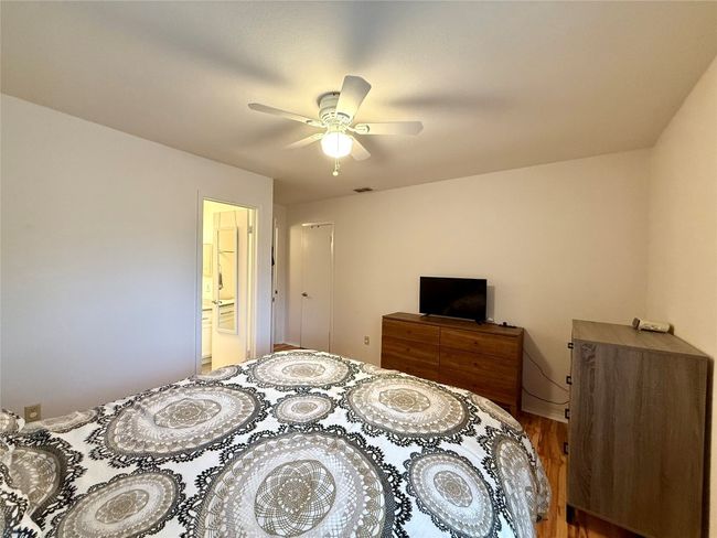 Bedroom with visible vents, ceiling fan, and wood finished floors | Image 11