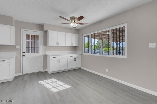 Kitchen with ceiling fan, baseboards, white cabinetry, and light wood finished floors | Image 18