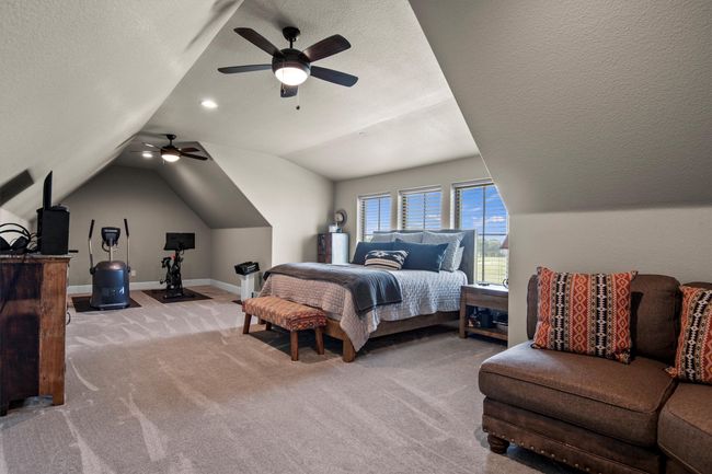 Carpeted bedroom with lofted ceiling, ceiling fan, and a textured ceiling | Image 27