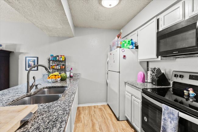 Kitchen featuring a textured ceiling, a sink, light wood-style floors, and stainless steel range with electric stovetop | Image 8