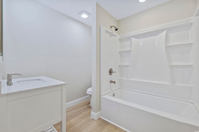 Full bathroom featuring toilet, vanity, wood finished floors, shower / tub combination, and baseboards | Image 29
