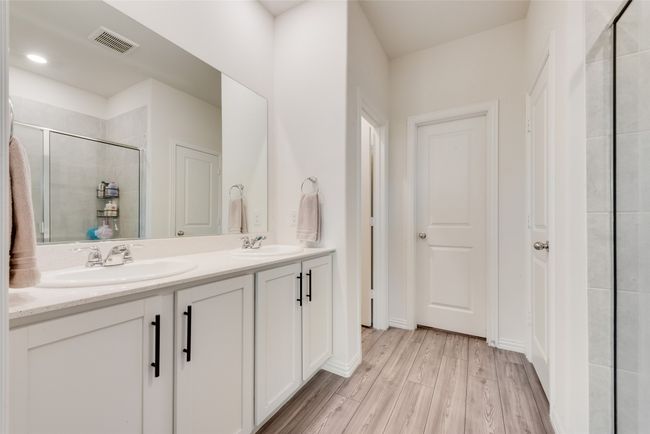 Bathroom featuring double vanity, a stall shower, and wood finished floors | Image 11
