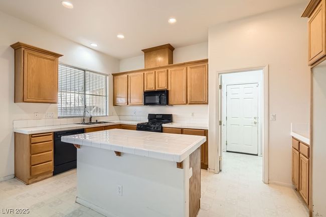 Kitchen with a sink, tile counters, recessed lighting, black appliances, and light floors | Image 10
