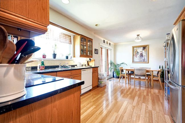Kitchen featuring white dishwasher, a sink, freestanding refrigerator, dark countertops, and brown cabinetry | Image 8