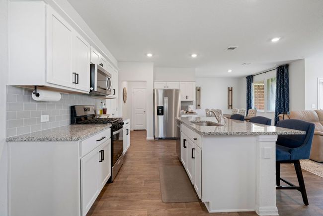 Kitchen featuring stainless steel appliances, a breakfast bar area, open floor plan, backsplash, and dark wood-type flooring | Image 12