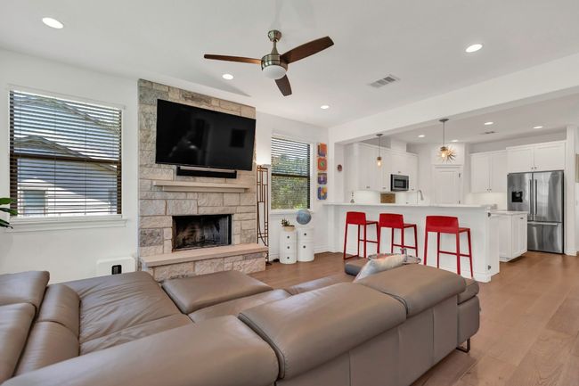 Living room with dark wood-style flooring, a ceiling fan, recessed lighting, and a fireplace | Image 9