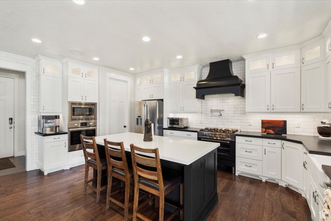 Kitchen featuring white cabinets, dark wood-style floors, premium range hood, and stainless steel appliances | Image 15