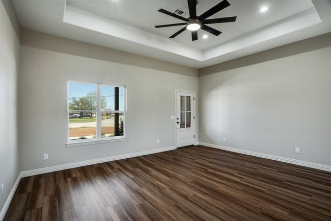 Spare room with baseboards, a ceiling fan, dark wood-style floors, and a raised ceiling | Image 5