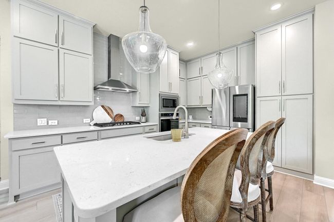 Kitchen featuring a sink, stainless steel appliances, light wood-type flooring, wall chimney range hood, and decorative backsplash | Image 11