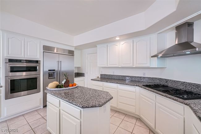 Kitchen with white cabinetry, light tile patterned floors, wall chimney exhaust hood, and appliances with stainless steel finishes | Image 28