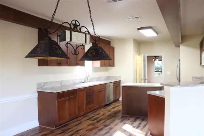 Kitchen featuring a sink, brown cabinets, stainless steel appliances, light countertops, and dark wood-style floors | Image 9