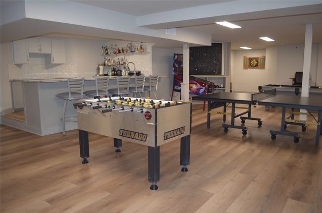Rec room basement featuring light wood-style flooring and bar area | Image 25