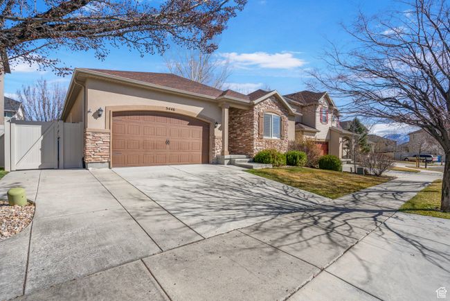 View of front facade featuring stone siding, a gate, driveway, an attached garage, and stucco siding | Image 4