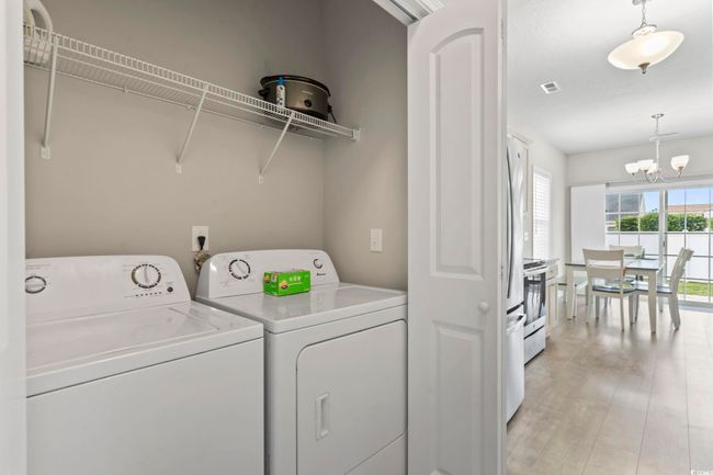 Laundry area with laundry area, an inviting chandelier, light wood finished floors, visible vents, and washing machine and dryer | Image 27