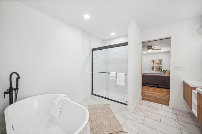 Ensuite bathroom featuring a soaking tub, connected bathroom, a shower stall, vanity, and baseboards | Image 16