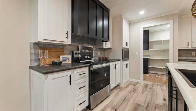 Kitchen featuring stainless steel appliances, tasteful backsplash, white cabinets, light wood-style flooring, and recessed lighting | Image 14