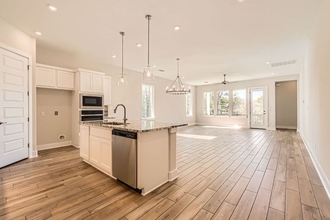 Kitchen with light wood finished floors, stainless steel appliances, white cabinets, a sink, and visible vents | Image 15