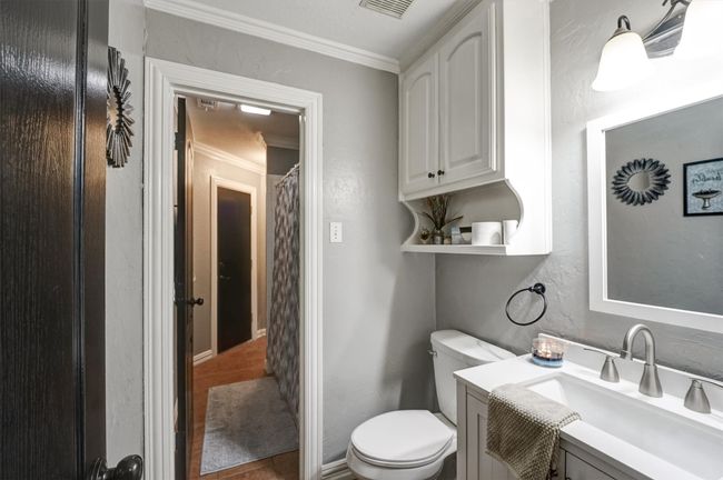 Bathroom featuring visible vents, toilet, a textured wall, crown molding, and vanity | Image 20